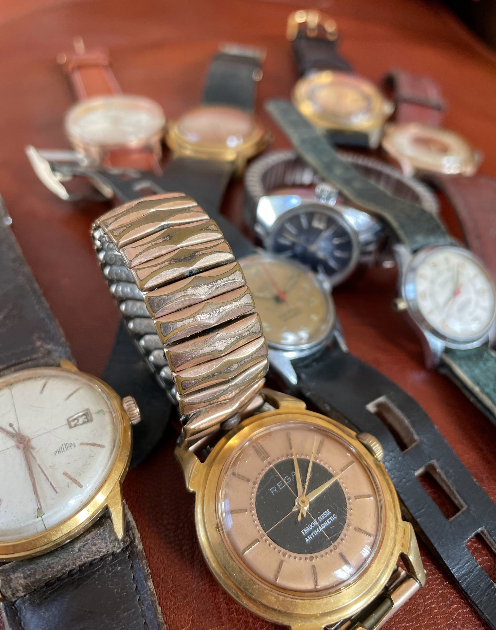 Lot de montres anciennes vintage dans leur jus de la remontrerie, horlogerie raisonnée. Au premier plan une montre mécanique française Philippe et une montre Rega.